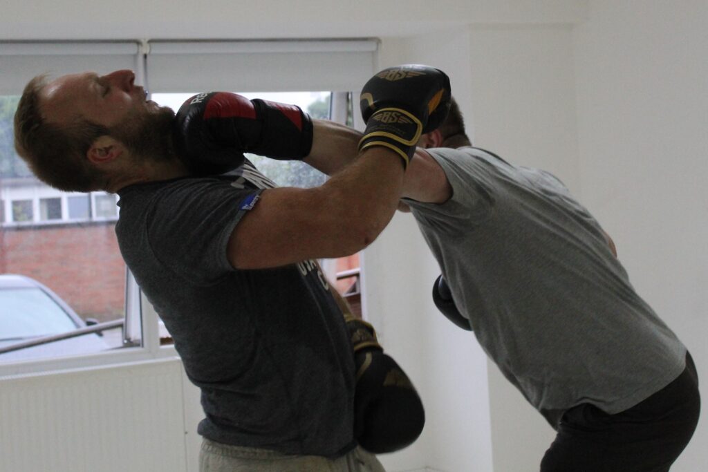 Two boxers sparring and one boxer getting hit