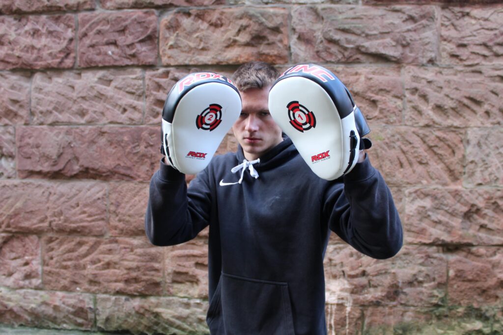 Boxer holding the pads for training boxing combinations