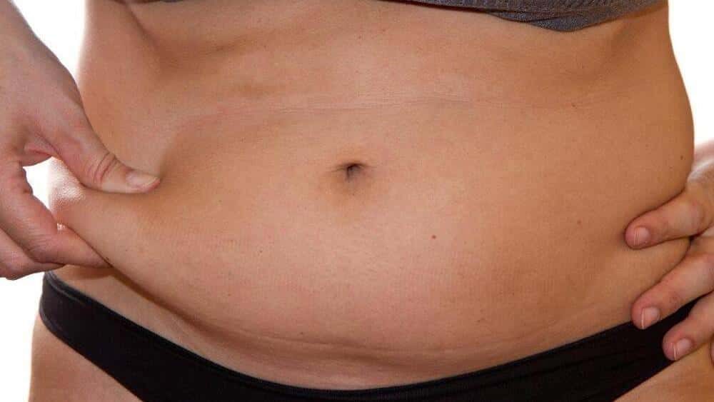 body-fat A woman pinching the fat in the stomach.
